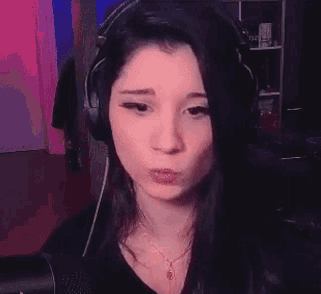 a woman wearing headphones is making a funny face in front of a microphone .