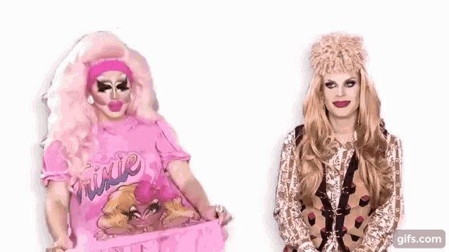 two drag queens are standing next to each other .