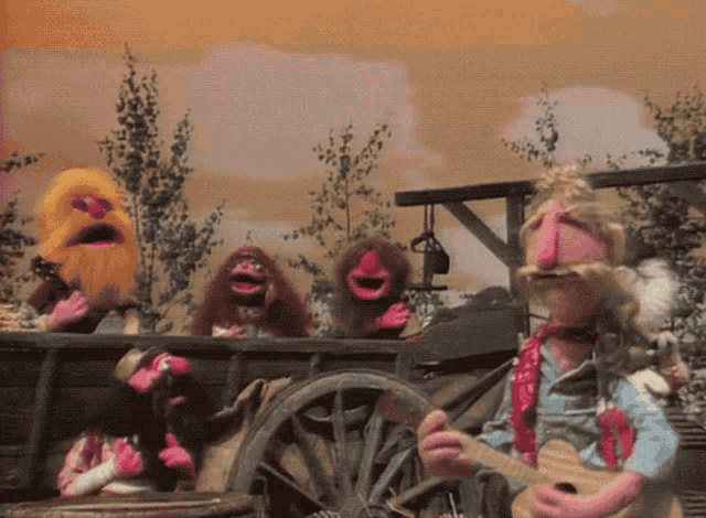a group of muppets singing and playing guitars in front of a wagon wheel