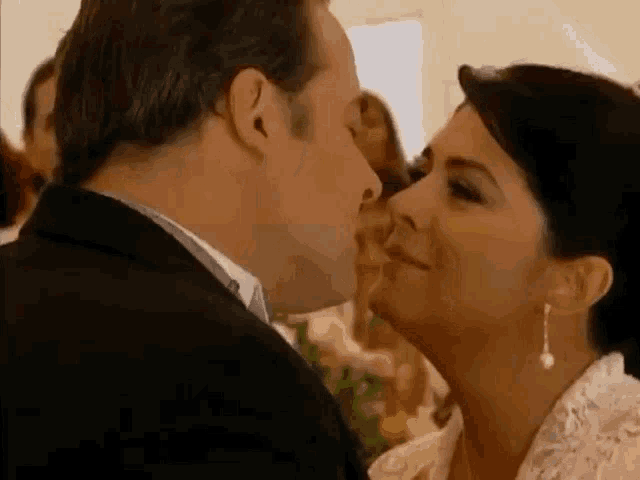 a man is kissing a woman on the cheek at a wedding ceremony .