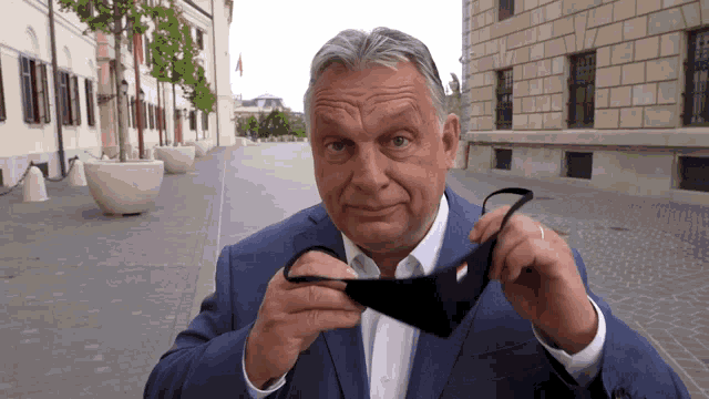 a man in a blue suit is holding a black mask