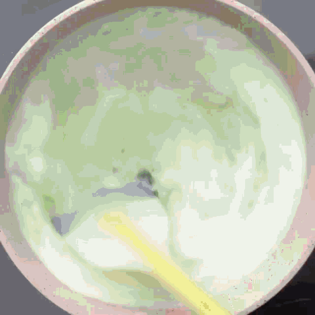 a bowl of green and white liquid with a yellow spoon
