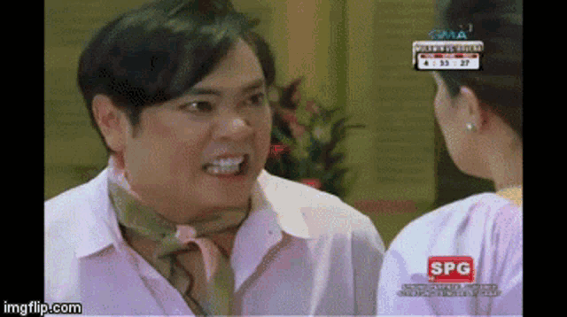 a man with a scarf around his neck talks to a woman on a spg channel