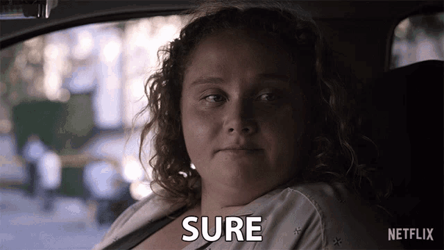 a woman sitting in a car with the word sure written on her face