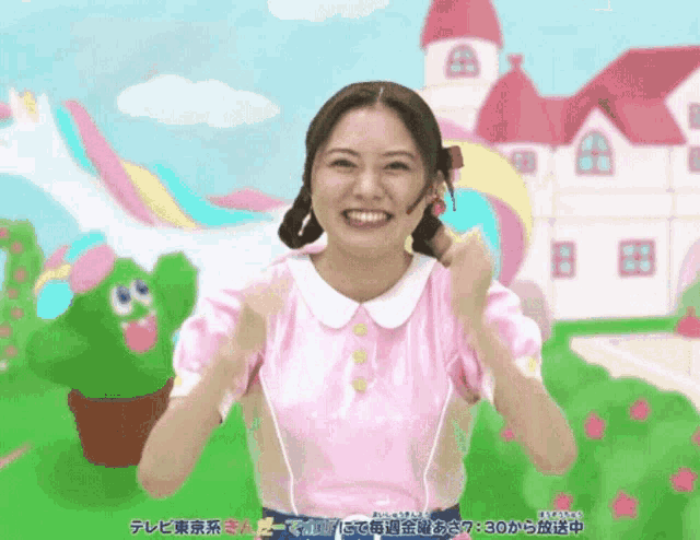 a woman in a pink top is smiling in front of a colorful castle