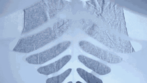 a person is cutting a piece of fabric into the shape of a skeleton on a white surface .