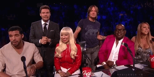 a group of people sitting in front of microphones with a coca cola can on the table