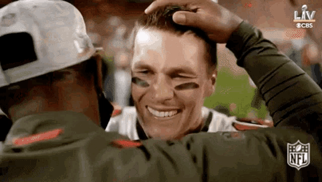 a man is touching another man 's head while they are smiling and hugging .
