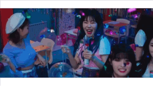 a group of girls are standing next to each other in a room holding balloons and confetti .