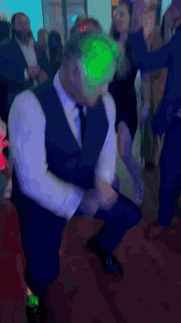 a man in a suit is dancing in a crowd of people at a party