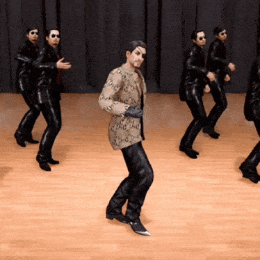 a group of men are dancing on a stage and one of them is wearing sunglasses