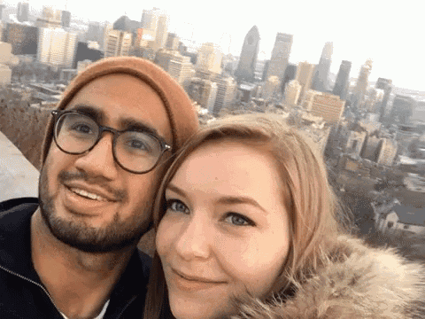 a man and a woman are posing for a picture with a city in the background