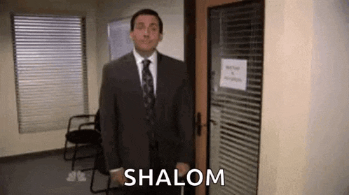 a man in a suit and tie is standing in front of a door with the words `` shalom '' written on it .