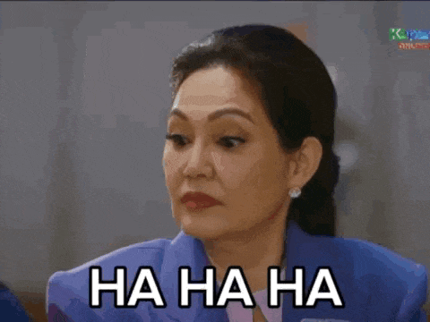 a woman in a blue suit is laughing and says ha ha ha