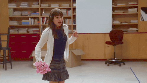 a woman holding a bouquet of pink flowers stands in front of a white board