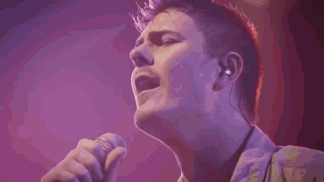 a man is singing into a microphone with a red background