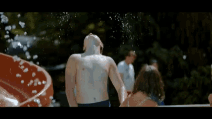 a man is splashed with water at a water park while a woman watches .