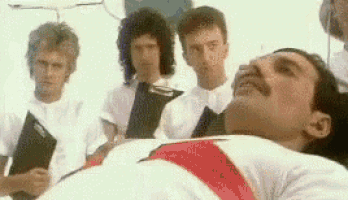 a man with a mustache is laying in a hospital bed with a group of men standing around him .