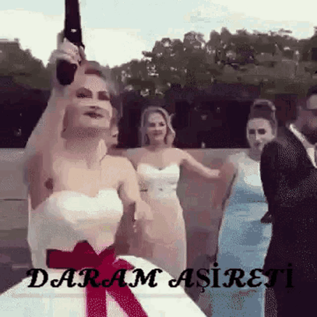 a bride in a wedding dress is holding a gun in her hand while dancing with her bridesmaids .