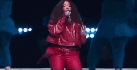 a woman in a red leather jacket is singing into a microphone .