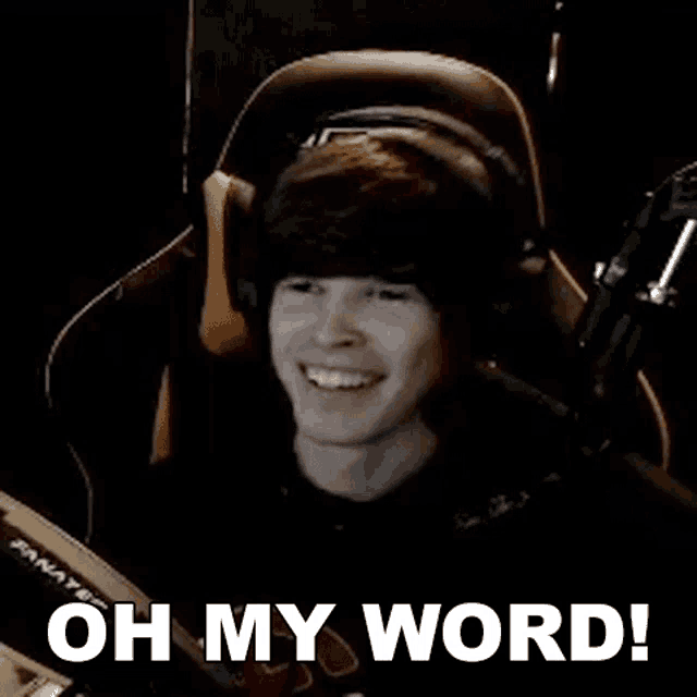 a young man wearing headphones is sitting in a chair in front of a microphone and smiling .