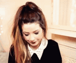 a woman with long hair is wearing a ponytail and a black shirt .