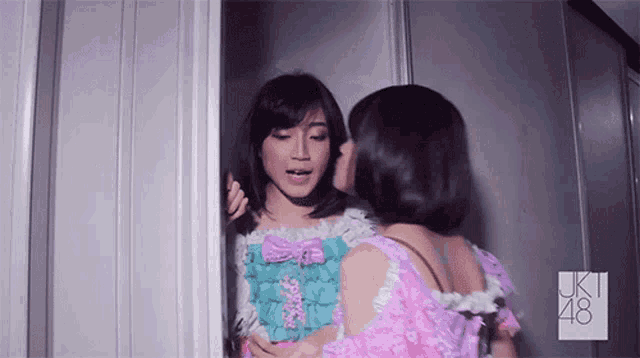 two girls are kissing in front of a sign that says uk 48