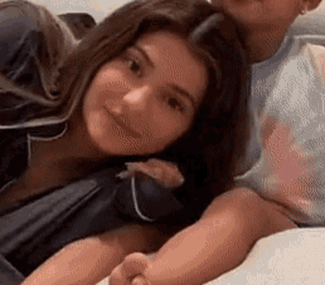 a man and a woman are laying on a bed and the woman is smiling .