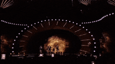a group of people standing on a stage with a lot of lights