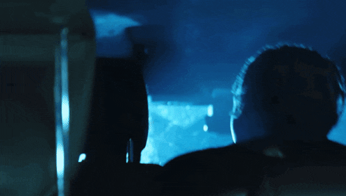 a blue light is shining on a person 's face in a dark room