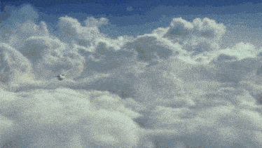 a plane flying through a cloudy sky with a blue sky in the background