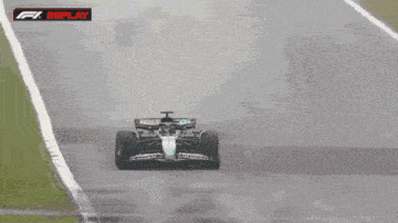 a race car is driving down a wet track with the words f1 replay on the bottom right