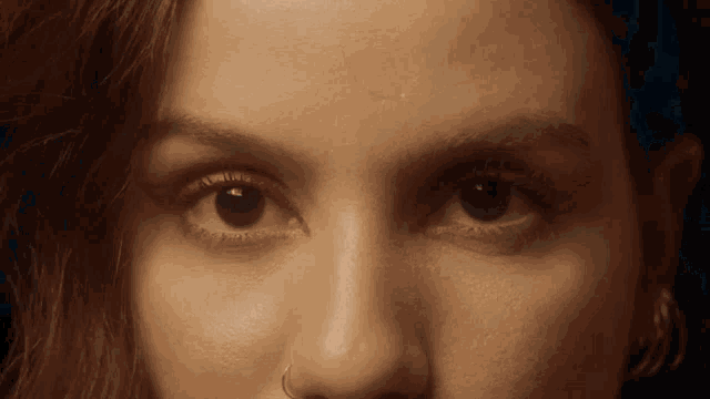 a close up of a woman 's eyes with red eye shadow and a nose ring