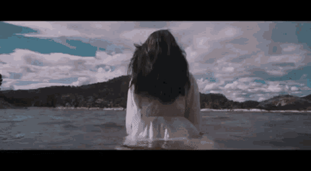 a woman in a white dress is standing in the middle of a lake .