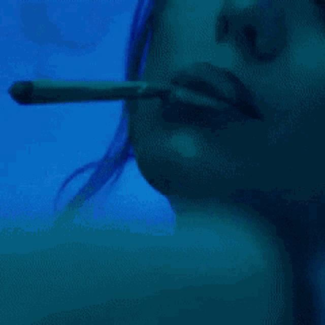a close up of a woman smoking a cigarette in front of a blue background