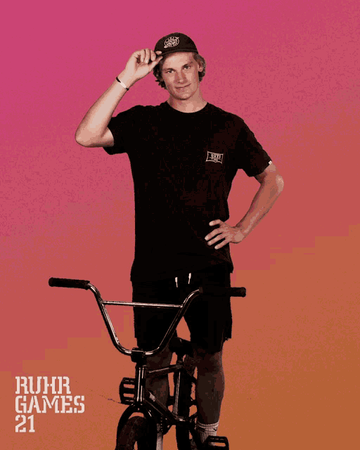 a young man stands next to a bike with ruhr games 21 on the bottom