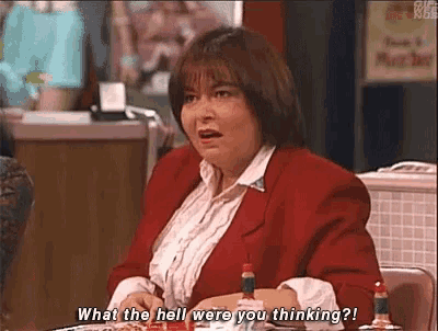 a woman in a red jacket is sitting at a table with a plate of food and asking what the hell were you thinking .