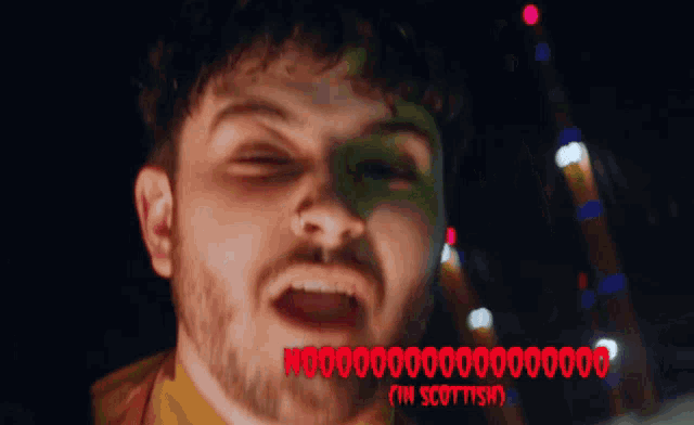 a close up of a man 's face with the words " in scottish " on the bottom right
