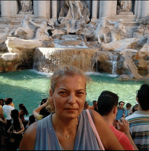 a woman is standing in front of a waterfall