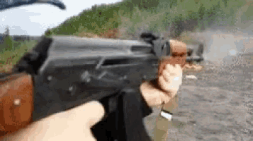 a person is holding a gun in their hand and pointing it at a body of water .