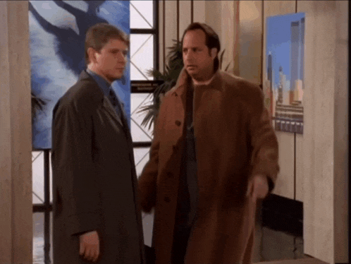 two men standing next to each other in a room