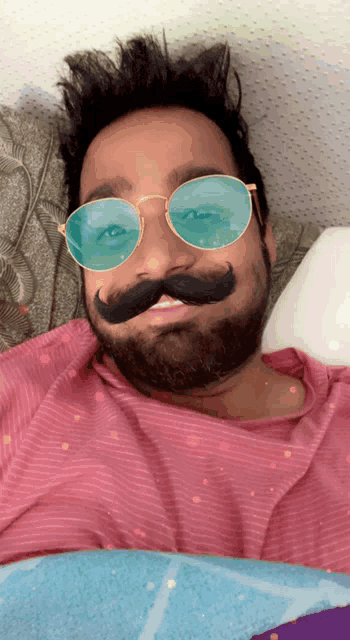 a man wearing sunglasses and a fake mustache is laying on a bed