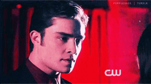 a man in a suit and tie is looking at a woman in front of a red wall .