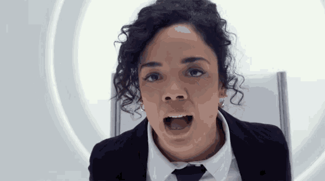 a woman in a suit and tie with her mouth wide open