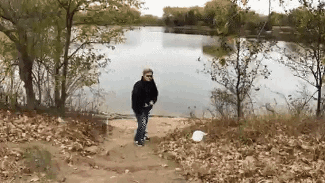 a man is throwing a frisbee in the air near a lake .