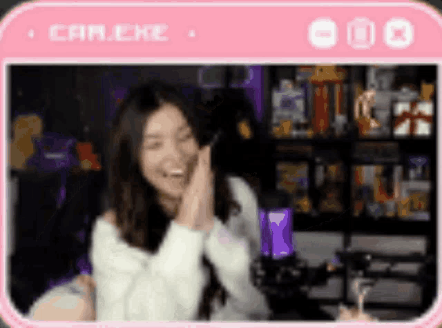 a woman is laughing while sitting in front of a microphone in a pink frame .