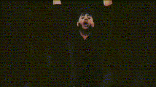 a group of people are standing in a dark room with their hands up