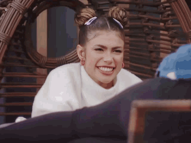a woman wearing a white sweater and hoop earrings smiles for the camera