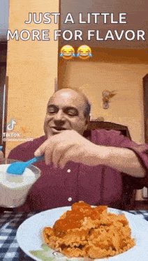 a man is sitting at a table with a plate of pasta and a spoon .