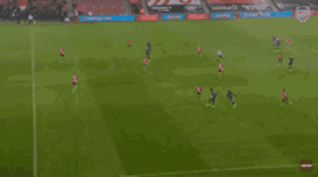 a blurred image of a soccer field with a few players in red and blue